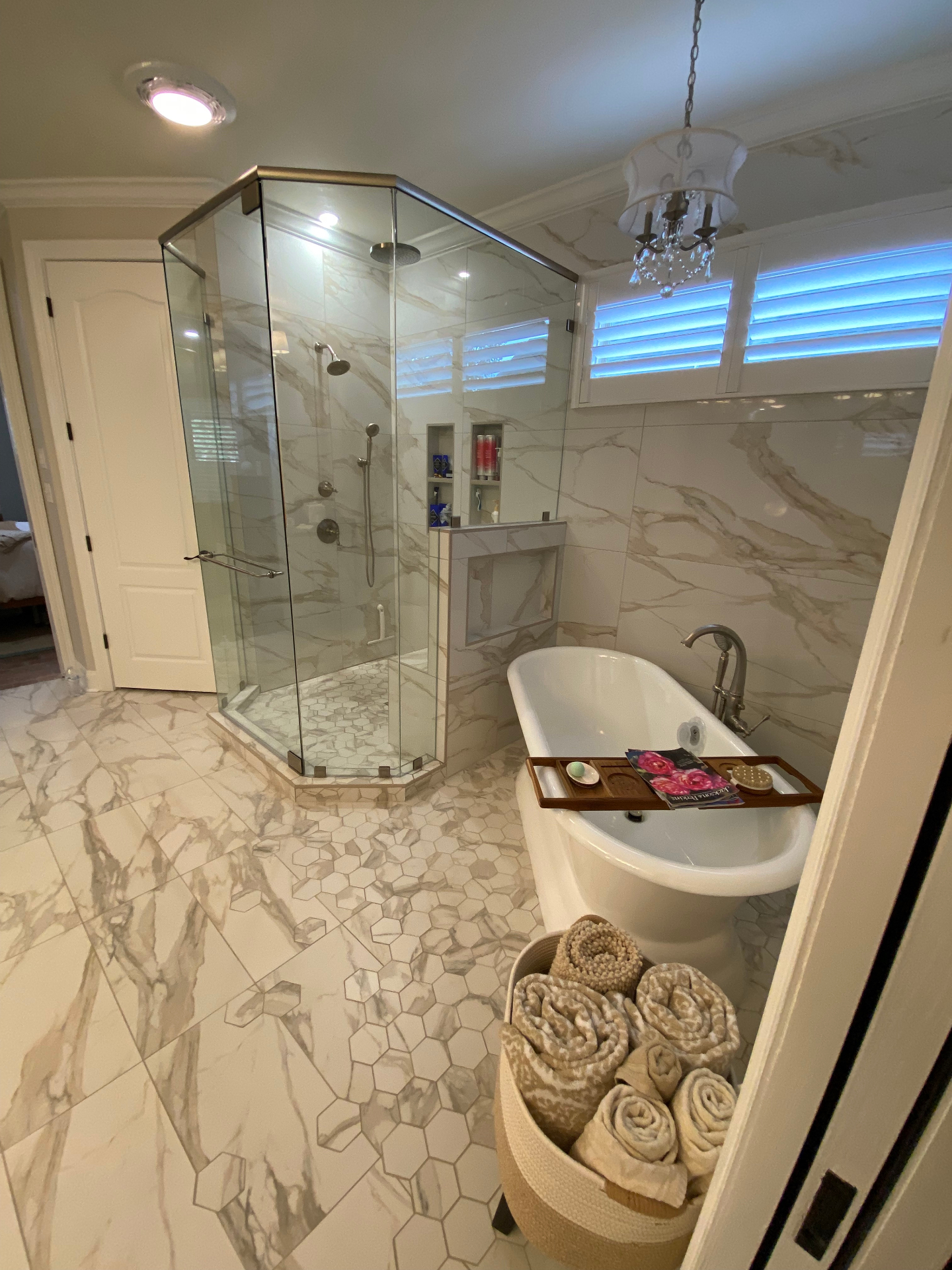 Glass shower enclosure with marble tile and freestanding tub